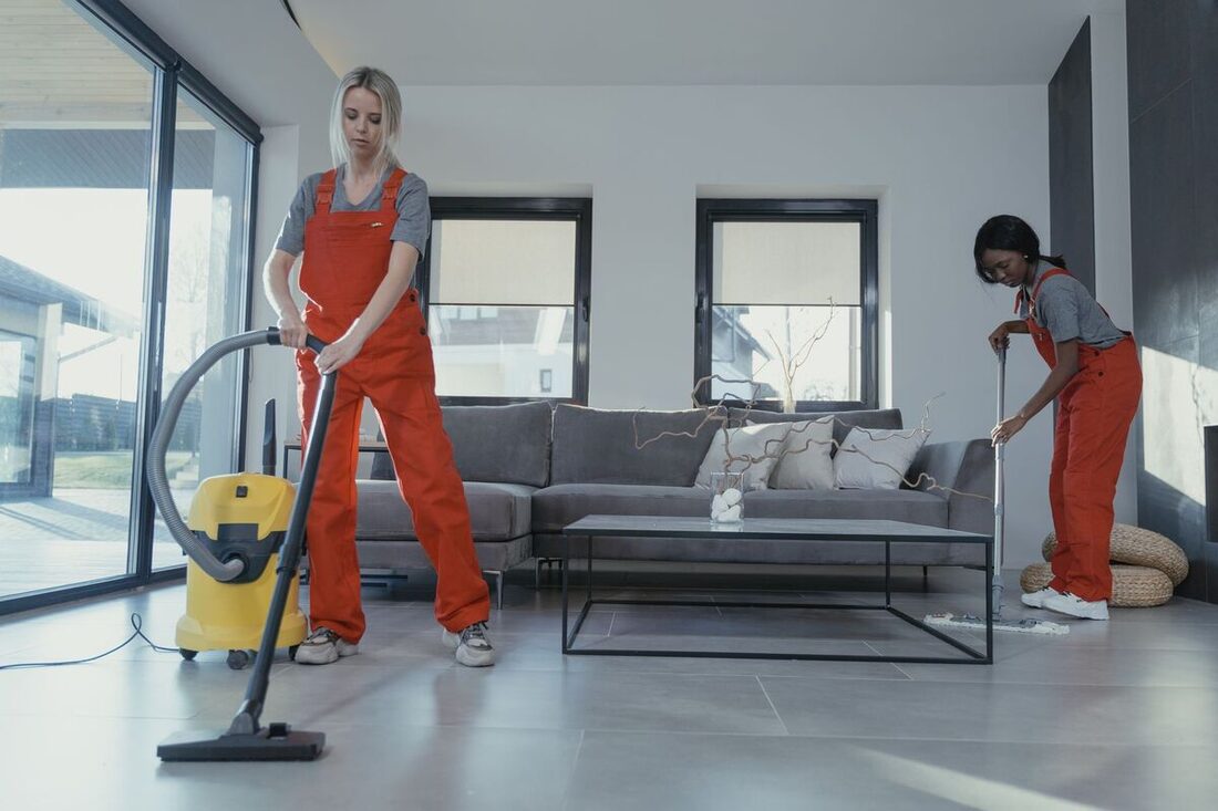 Two uniformed cleaners cleaning a bright Nashville living room