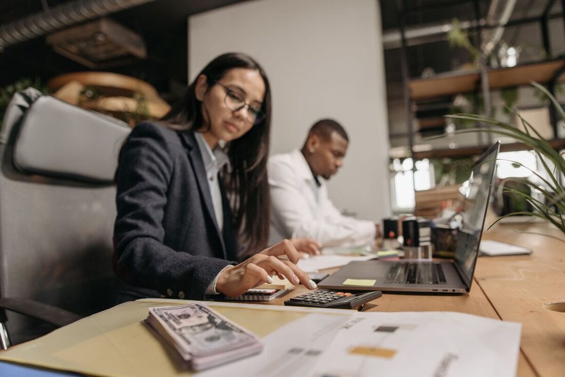 Accountants reviewing documents with a calculator and laptop