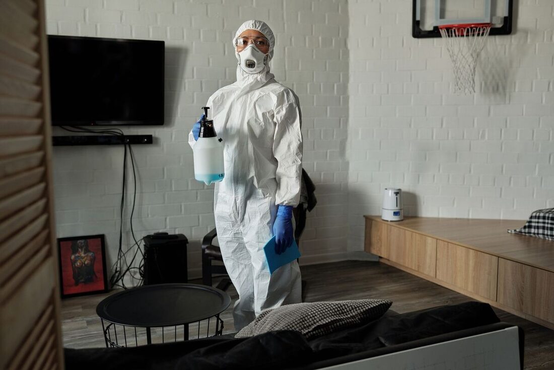 Technician in protective gear treating a living room